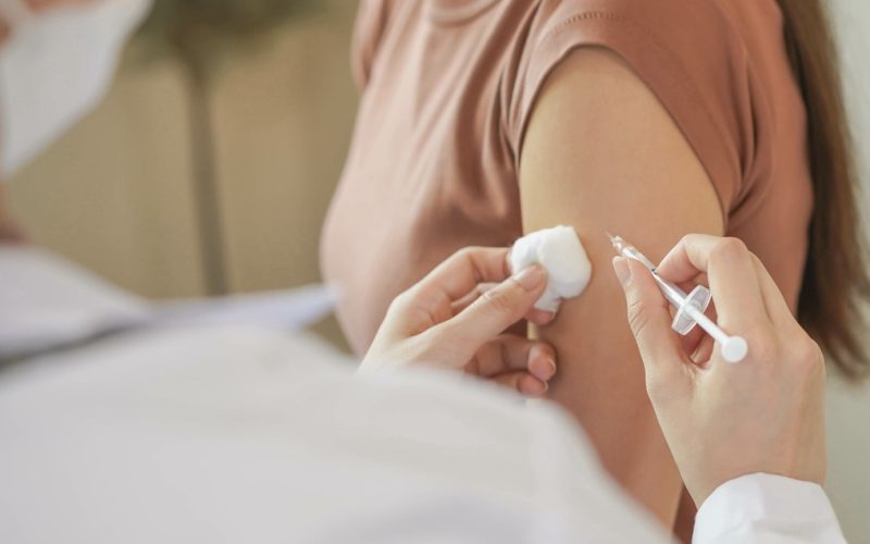 Covid-19,coronavirus hand of young woman nurse,doctor giving syringe vaccine, inject shot to asian arm's patient. Vaccination, immunization or disease prevention against flu or virus pandemic concept.