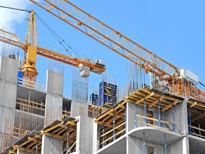Crane and building construction site against blue sky
