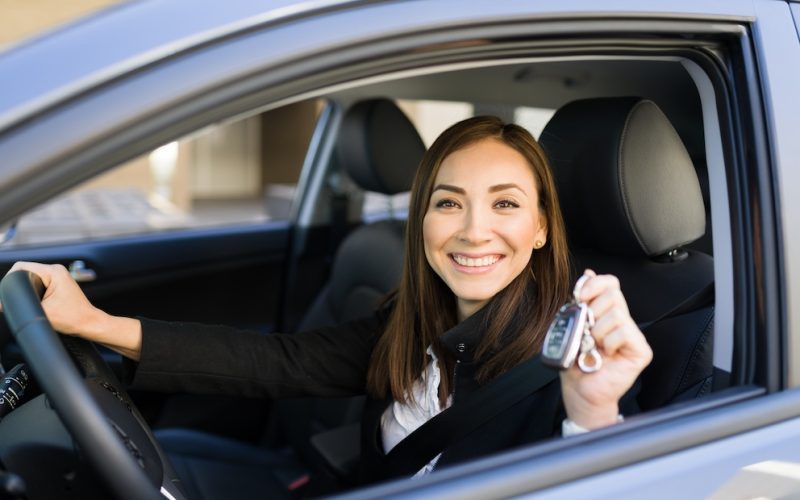 Successful caucasian woman showing the car keys of her car and smiling while sitting in the driver's seat. Business woman buying a new car