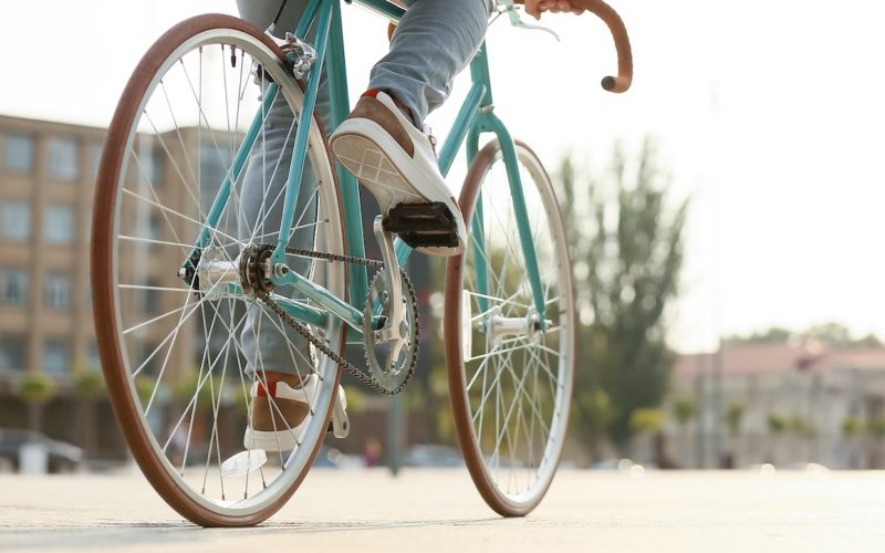 Young man riding bicycle on city square, closeup