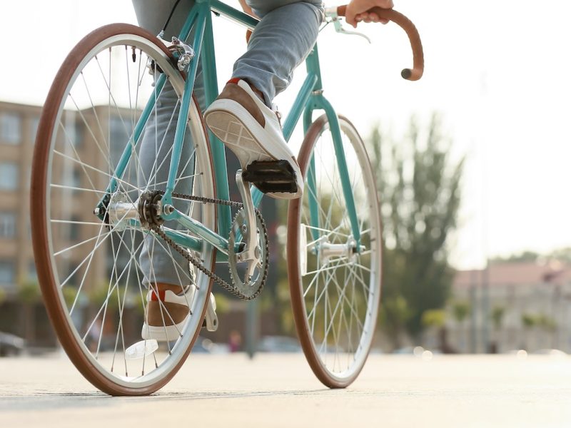 Young man riding bicycle on city square, closeup